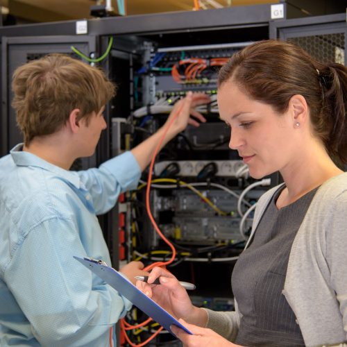Team of IT specialists in datacenter working by network servers